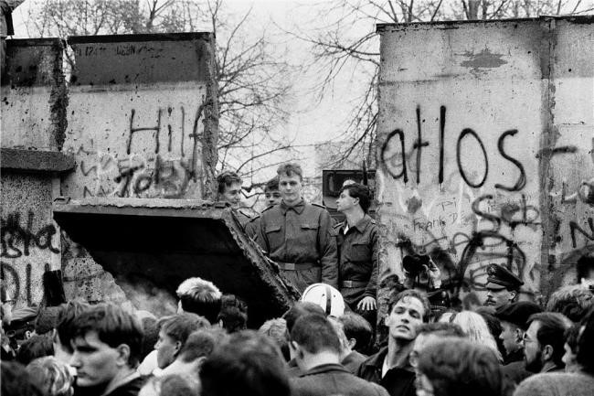 Brüchiger Beton in Berlin: Die Mauer muss weg - hunderte Menschen riefen dies im November 1989 und ließen ihren Worten auch Taten folgen. Hier sieht man ein Stück der Betonwand in Berlin nahe dem Brandenburger Tor. Von Westen aus versuchten Ost- und Westberliner, ein Loch in die Mauer zu reißen. Auf der anderen Seite stehen DDR-Grenztruppen, die sich bemühen, die Grenze abzusichern.